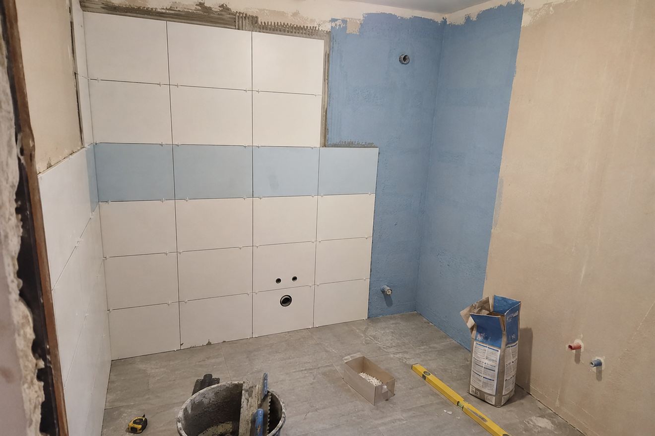 Kupaonica u fazi radova, zid s nanesenom hidroizolacijom i djelomično postavljene bijele pločice
